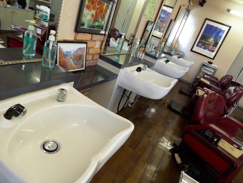 A row of white shaving basins facing red reclining chairs