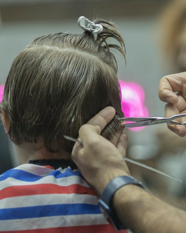 A stylist combing and scissor-cutting the back of a client's hair
