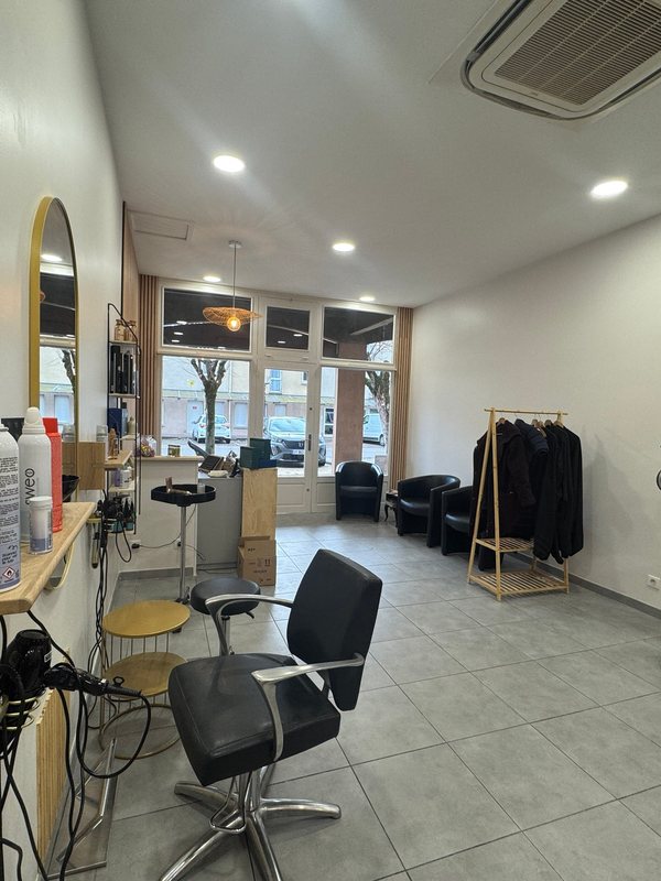 A styling station with a round mirror, chair and window light