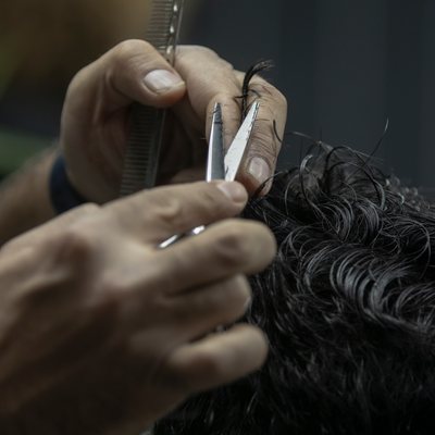 Hands working shears and a comb through curly hair