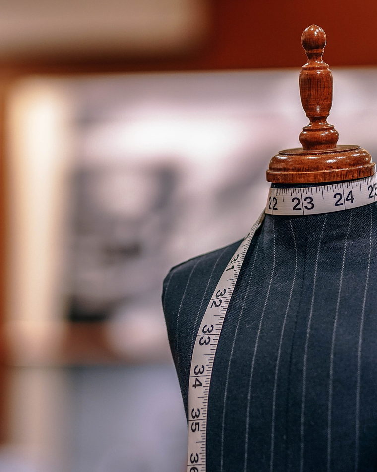 A dressmaker's mannequin with a yellow tape measure hanging over one shoulder.