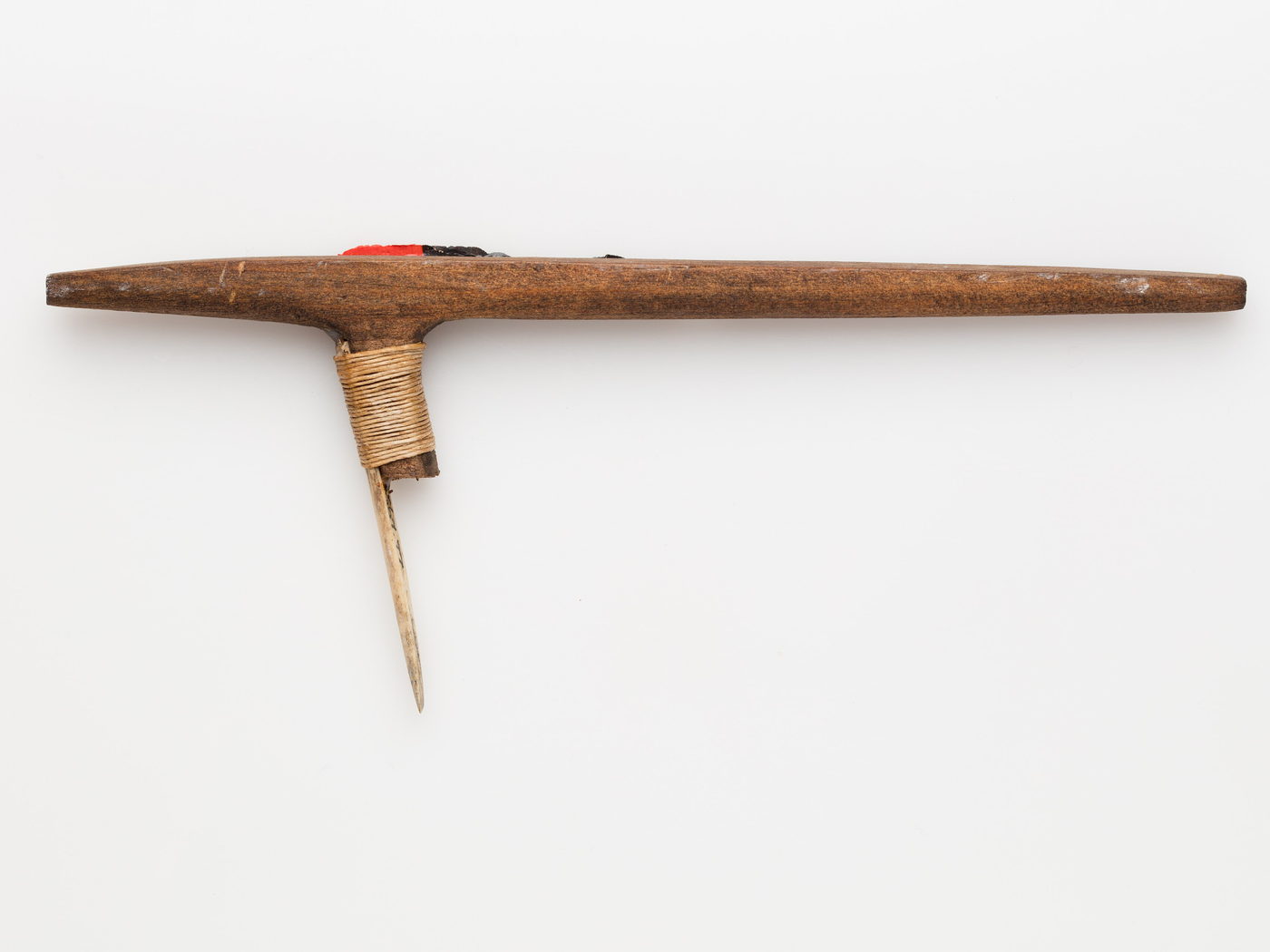A traditional hand-poke tattoo tool isolated on a pale gallery ground.