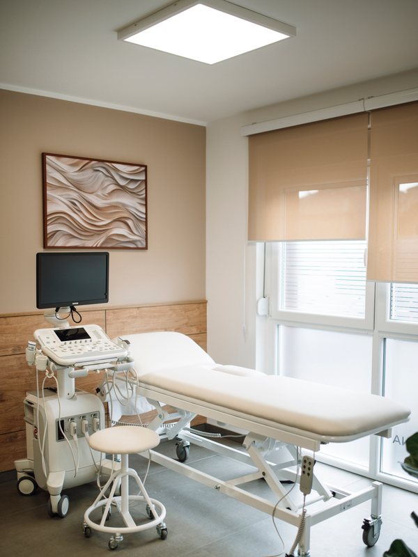 Examination room with an ultrasound unit beside a white treatment couch
