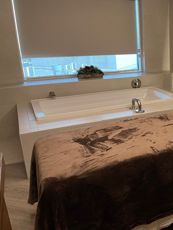 Quiet recovery room with a soft-lit tub and a draped treatment table