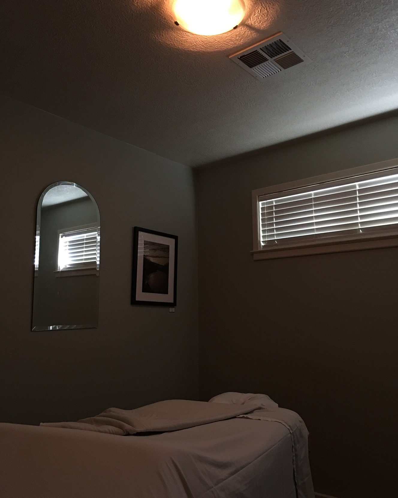 A massage couch made up with clean linen in a quiet, low-lit treatment room.