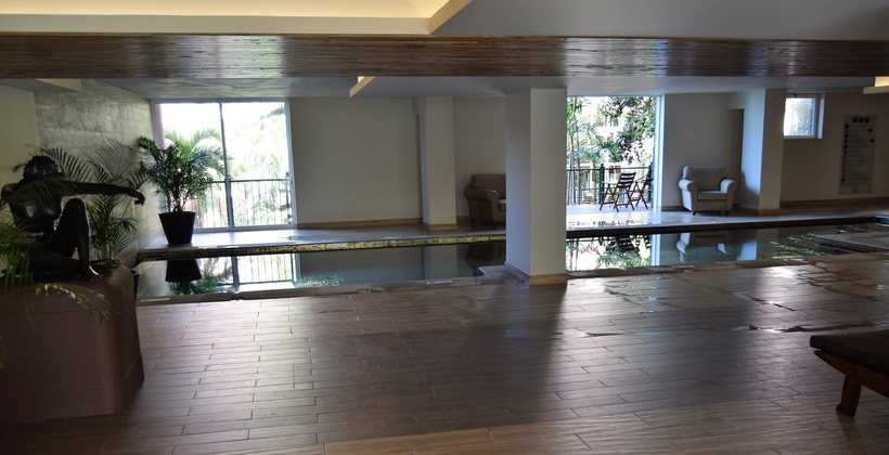 The studio's water room — a still shallow pool, potted greenery and tall windows