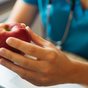 A hand holding a red apple