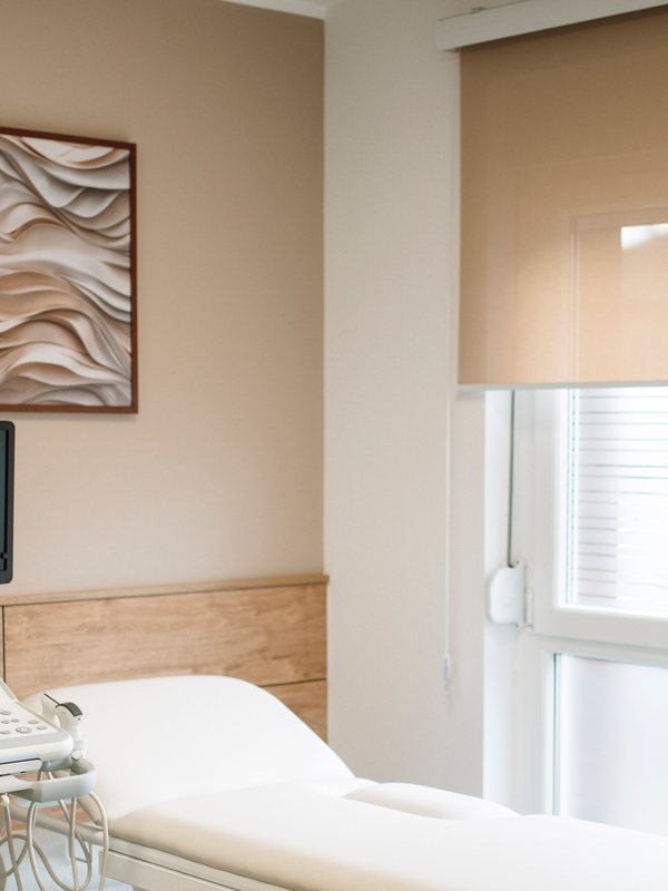 Treatment couch beneath framed textured artwork beside a shaded window