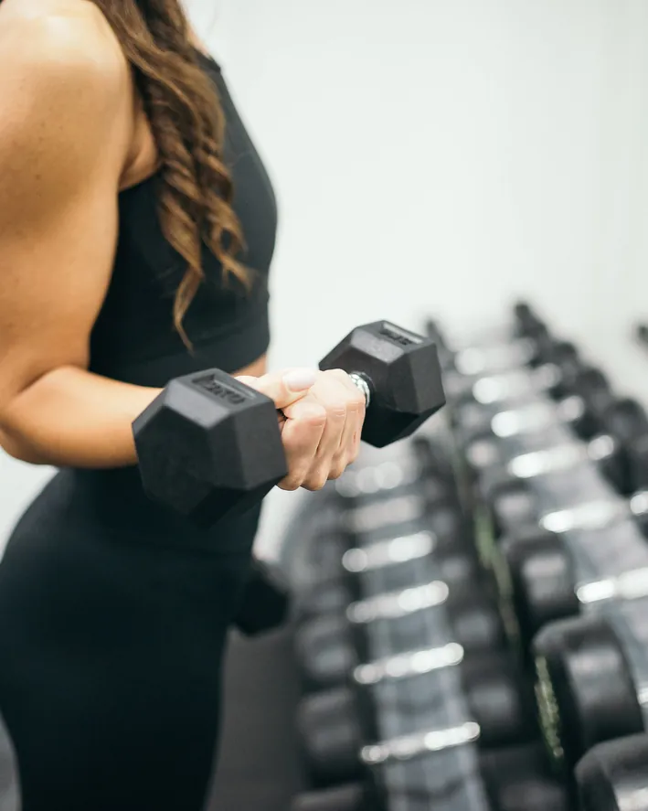 Vertical crop of a dumbbell and anonymous coaching hands