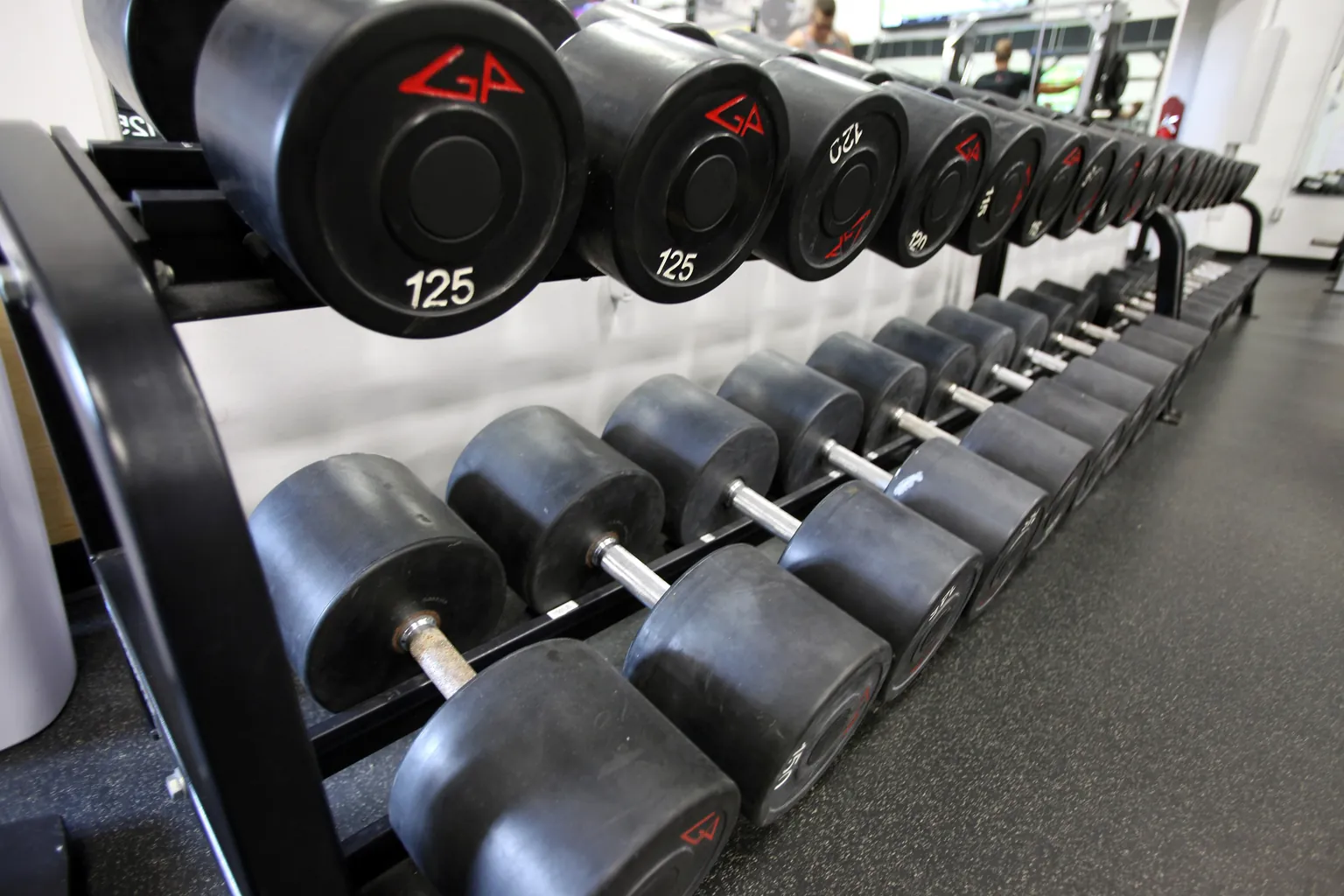 Dumbbells racked in weight order beside the floor