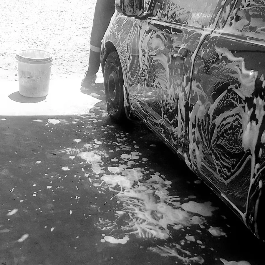 Square crop of a foam-covered car side and a wash bucket