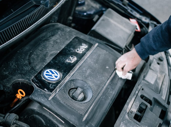 An engine bay being wiped down by hand with a cloth
