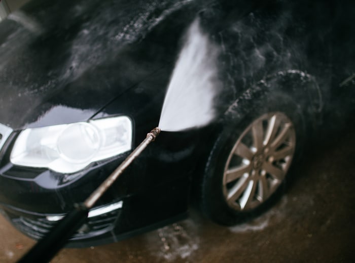 The lance working across the front wing of a black car, headlight and wheel rinsing clean
