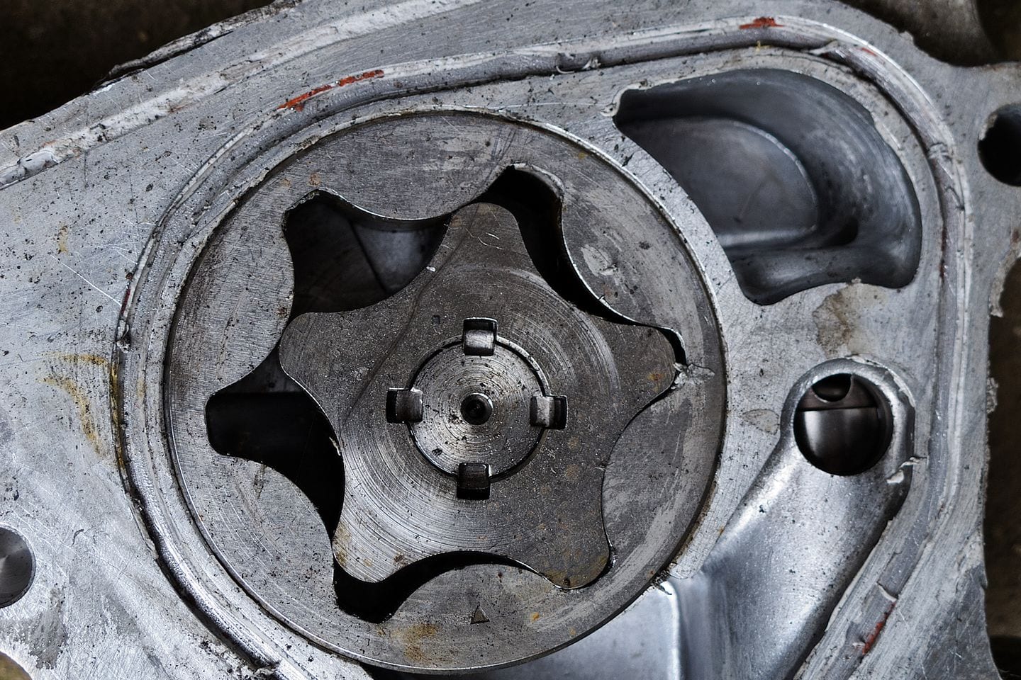 An oil pump removed from an engine and photographed on a bench, its housing and drive visible.