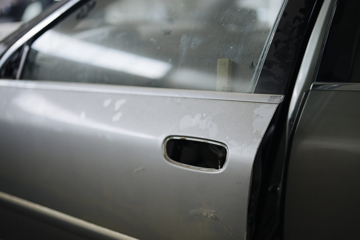 A silver car door panel showing paint wear along its lower edge.