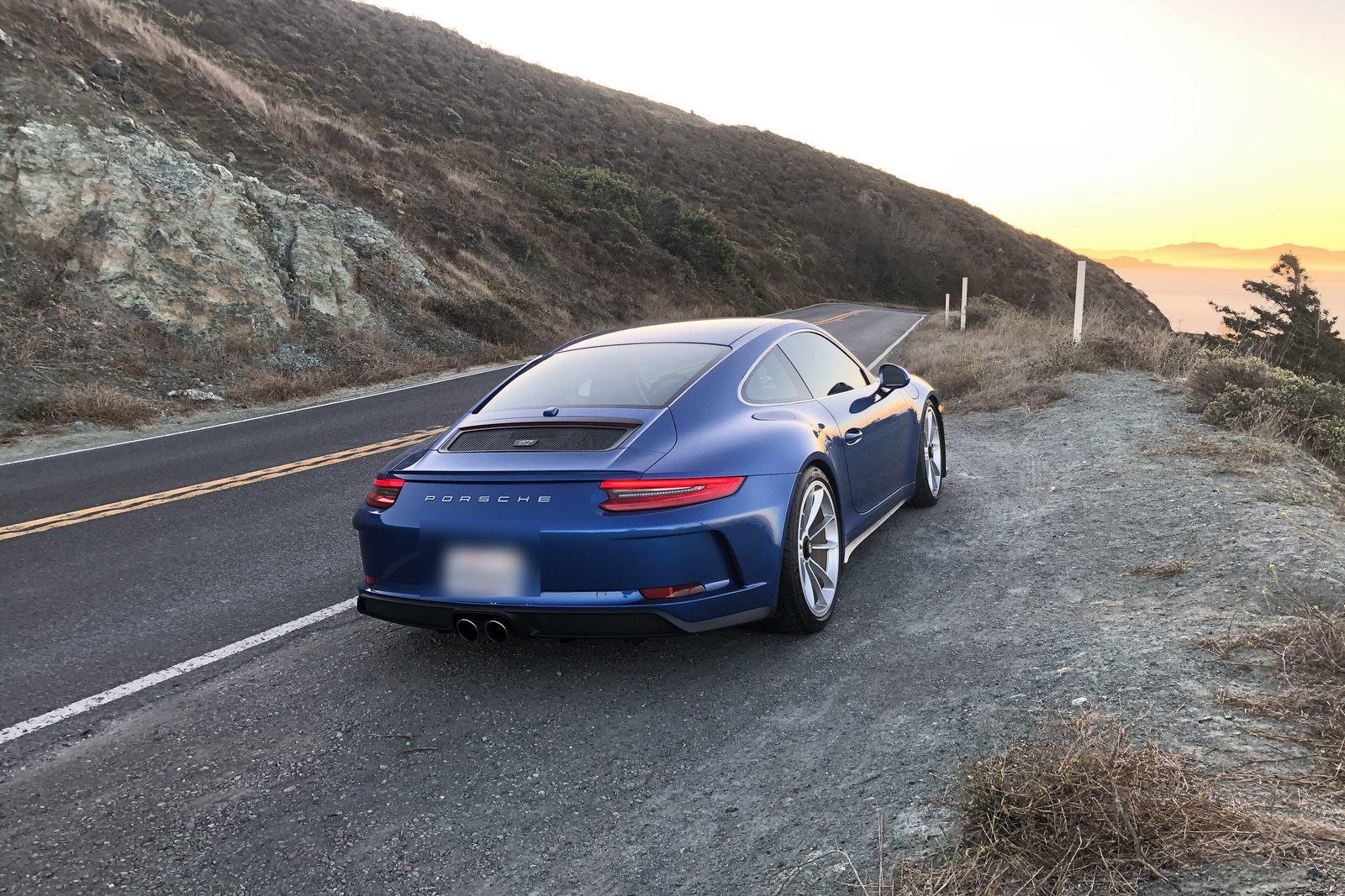 A Porsche 911 GT3 Touring on a coast road at dusk