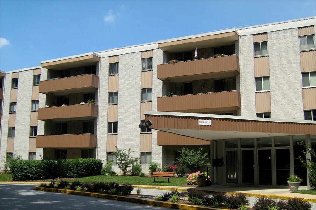 A tall brick and concrete condominium building seen from the street below.
