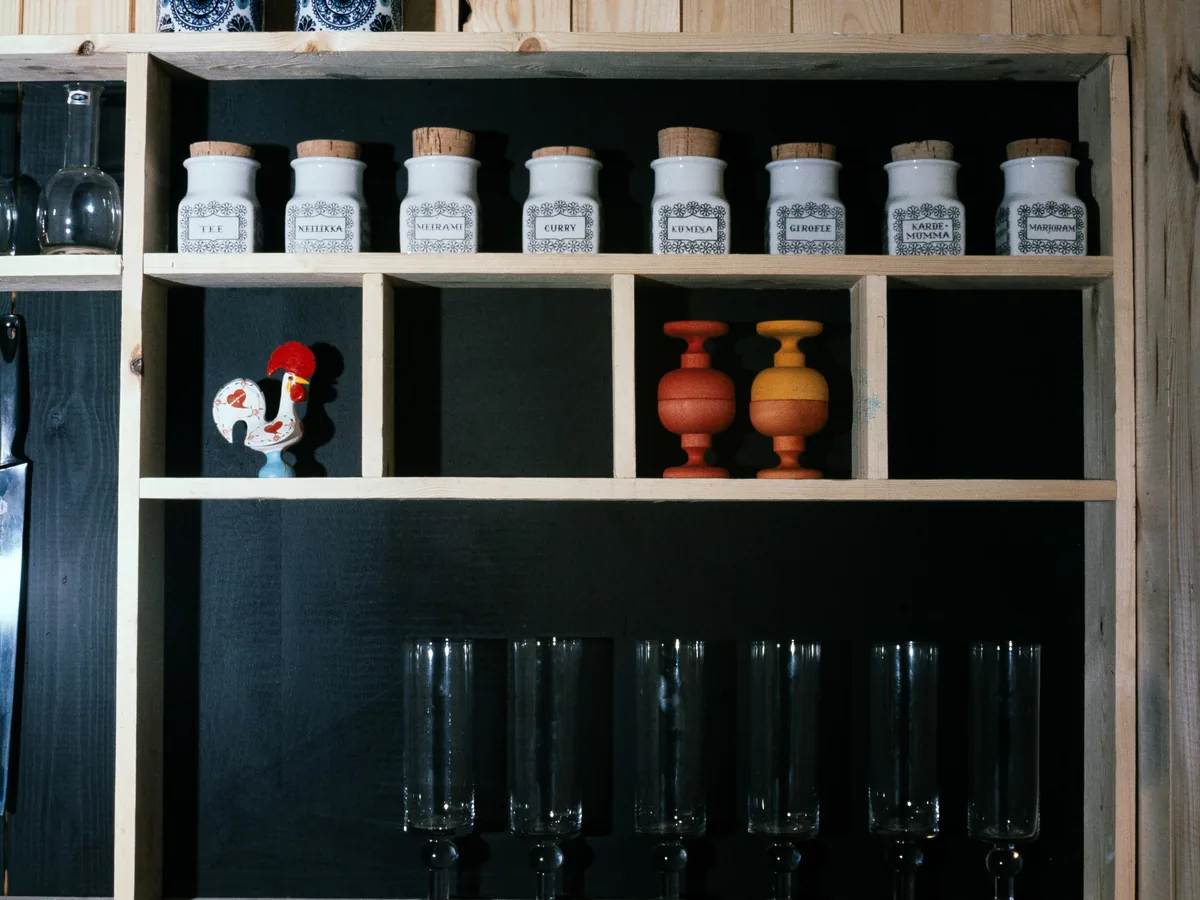 Dark fitted shelving holding glassware and storage jars