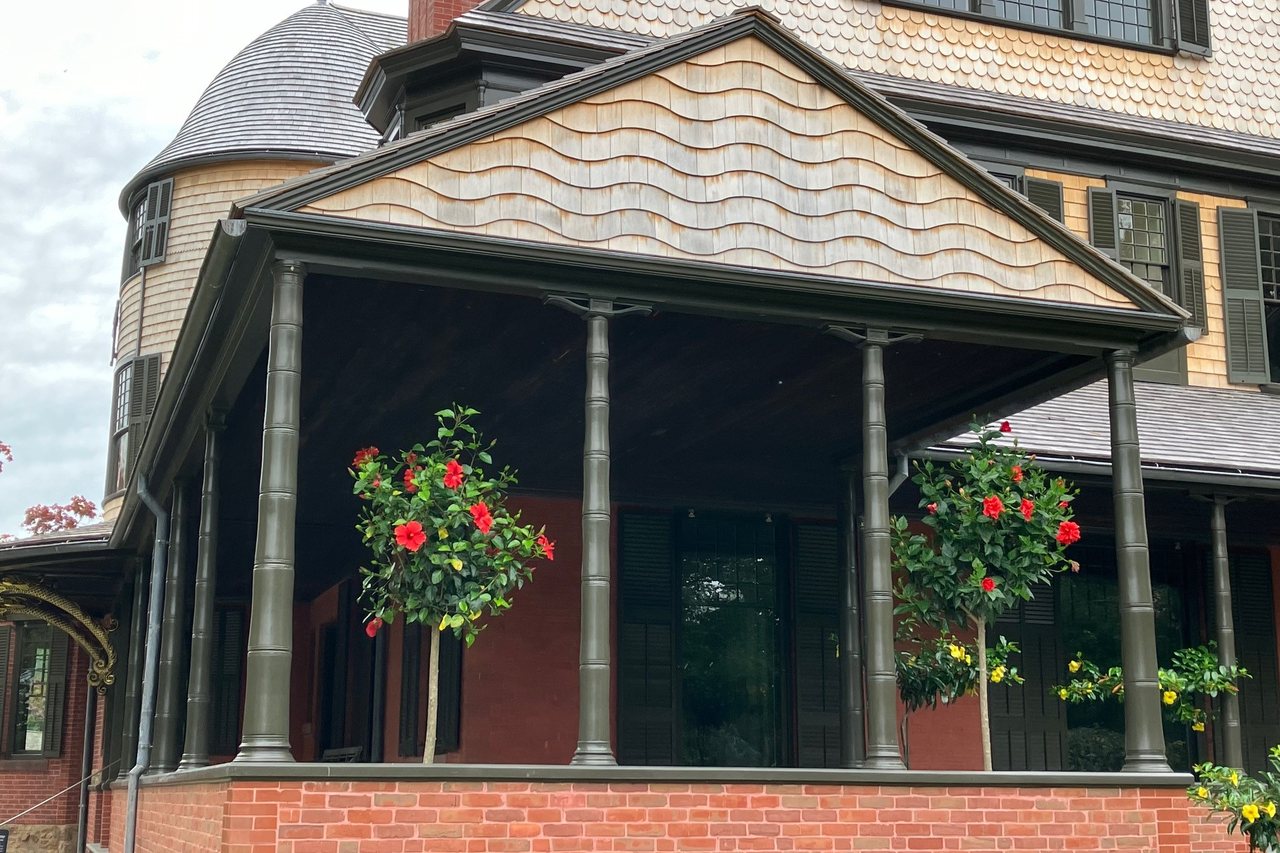 Wide covered porch with hanging flowers looking toward the water