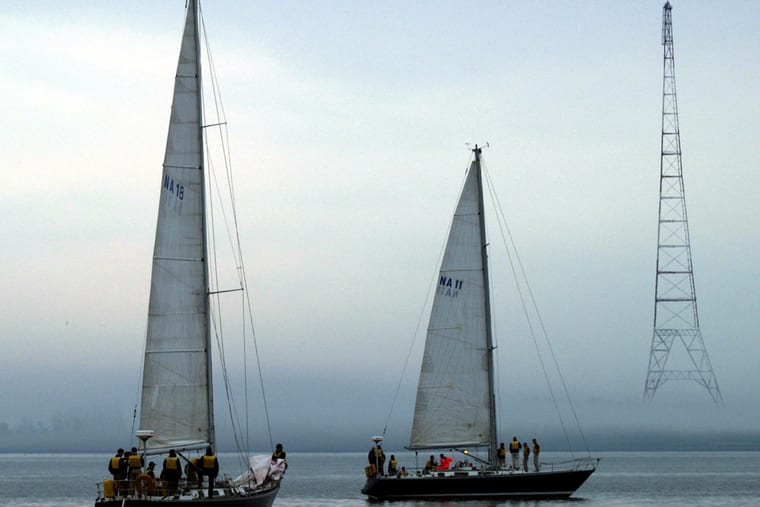 Two sailing boats with crew on deck, seen in flat grey fog.