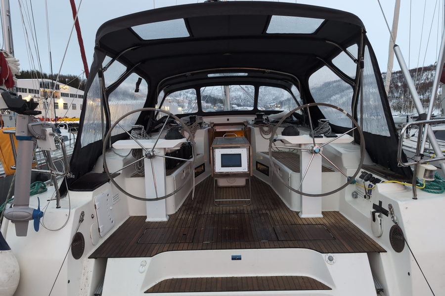 The twin-wheel cockpit of a cruising yacht under its fitted winter canvas.