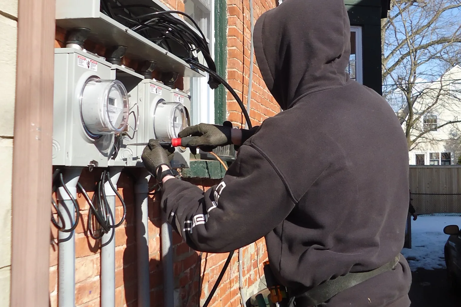 A technician testing supply meters on an exterior service wall