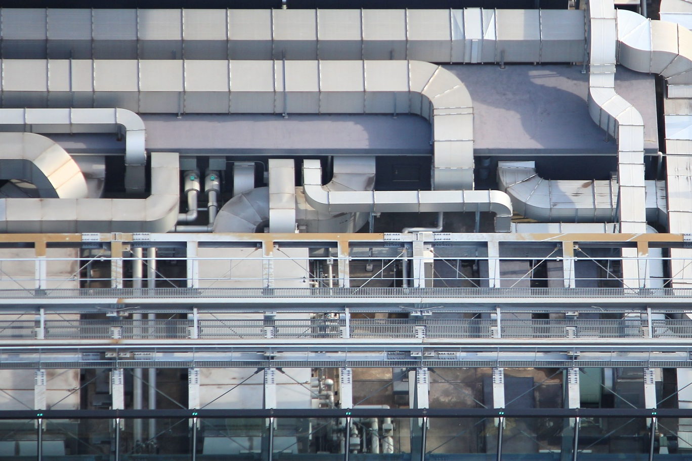 A packaged rooftop air conditioning unit on a flat office roof, with its access panels and duct connections visible