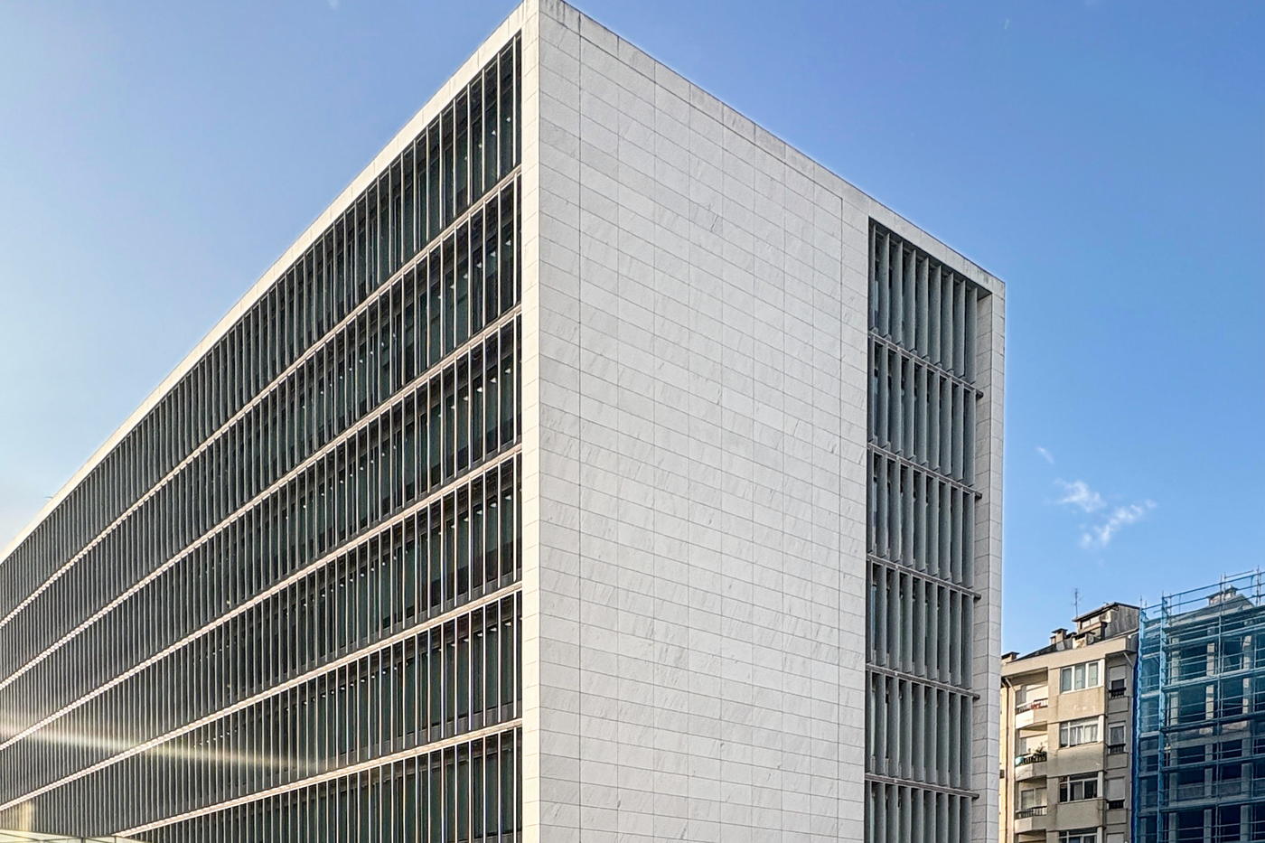 A modernist office block seen from below, its concrete grid of identical windows running the length of the facade.