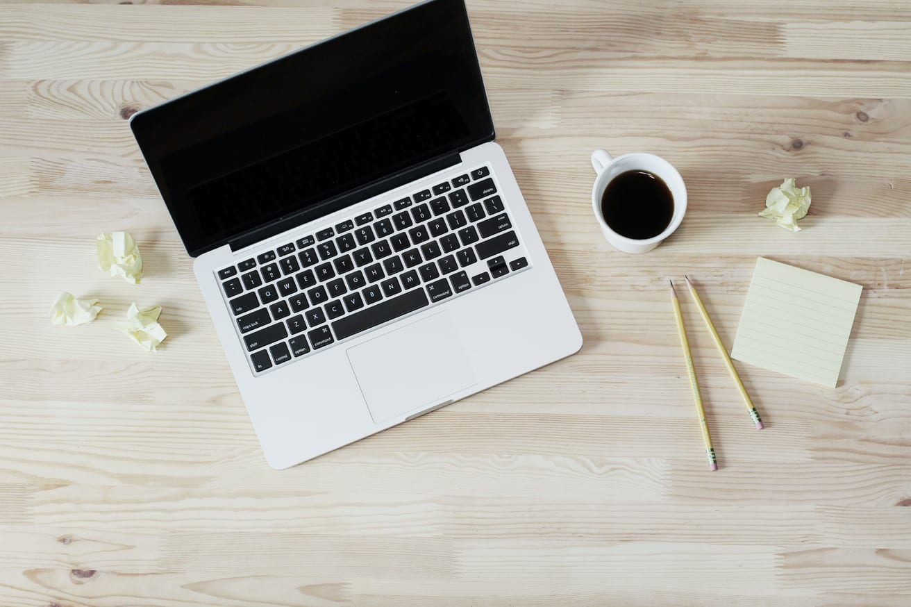 An open laptop and a cup of coffee on a desk.