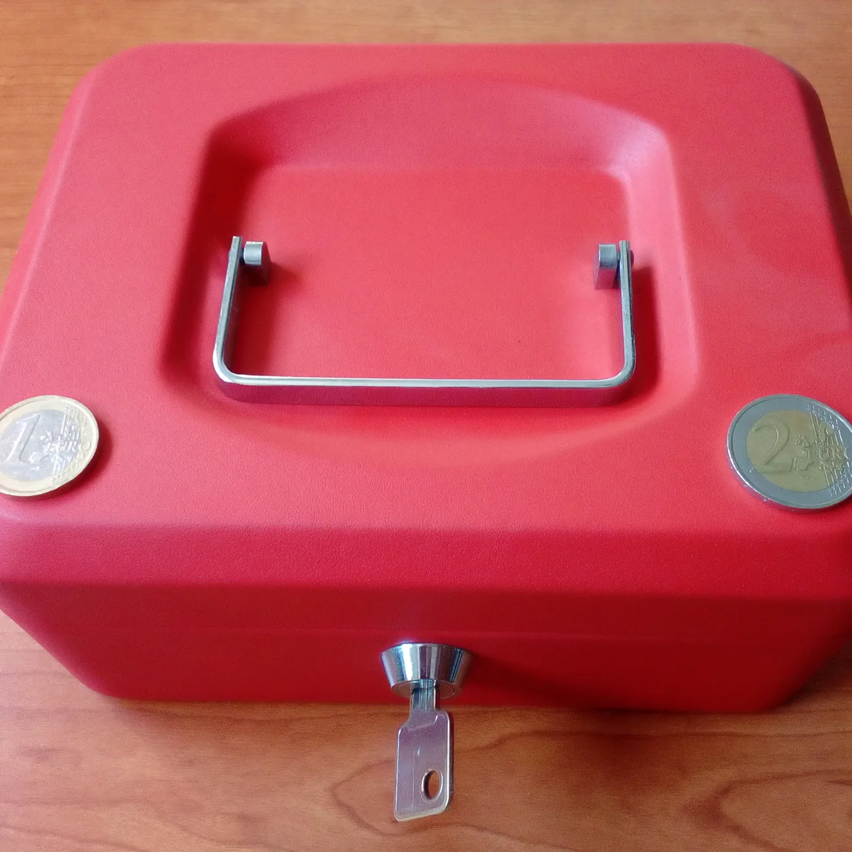 A small red cash box with the key in the lock