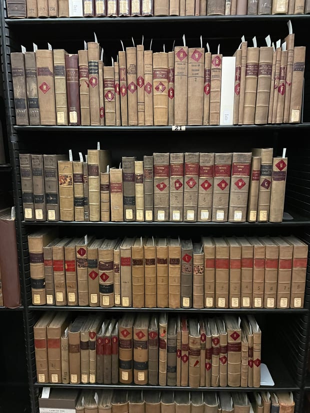 A shelf of older bound law reports standing behind a glazed door.
