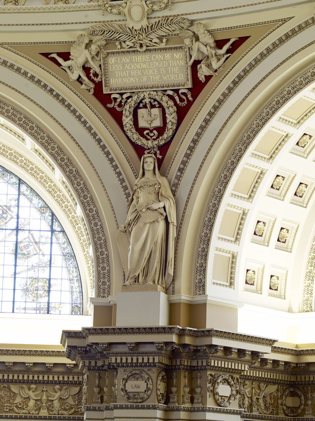 A carved figure of Law set on the stone entablature between two reading-room alcoves.