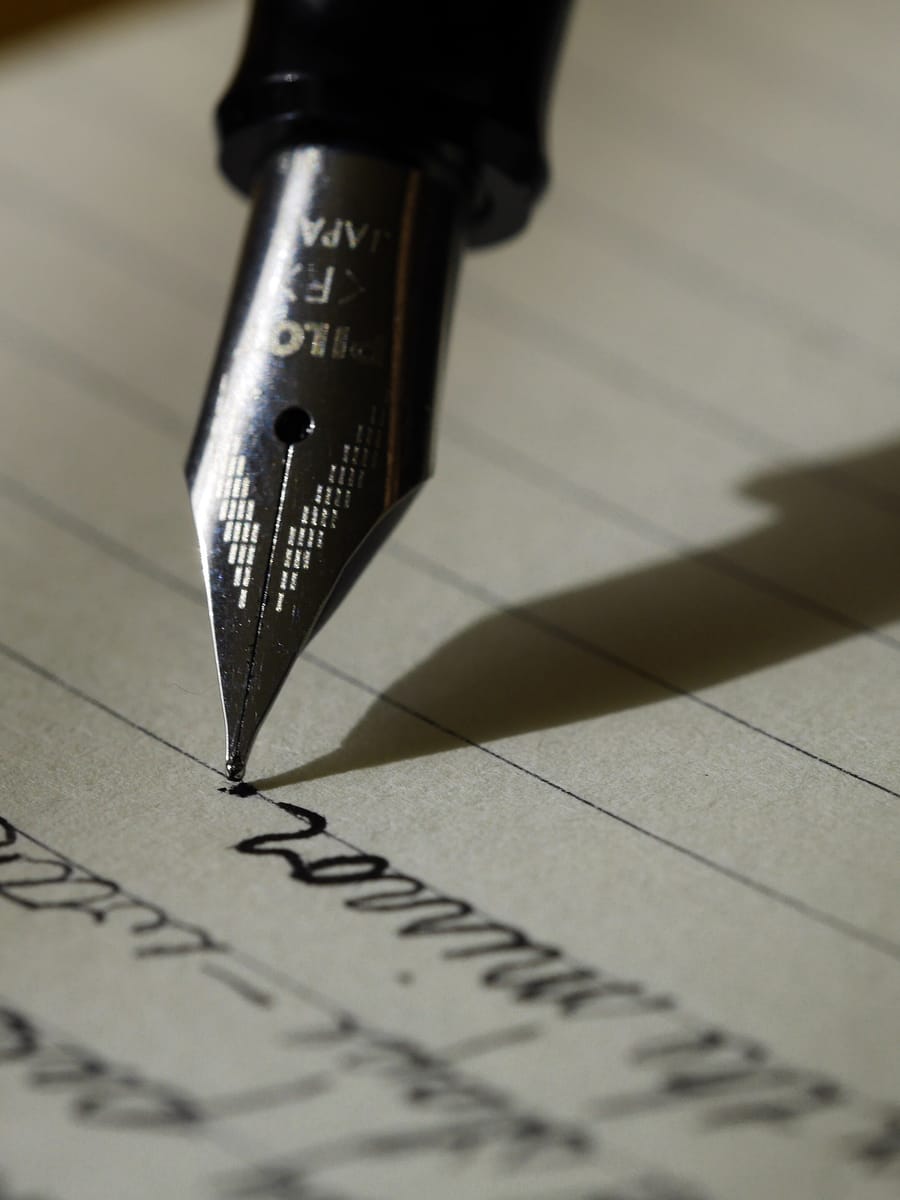 A close view of a fountain pen nib writing in ink on lined paper.