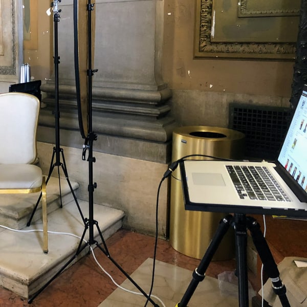 A sitting under way: the posing chair and reflector panel, the tether cable across the floor and a laptop on its stand showing the frames already taken
