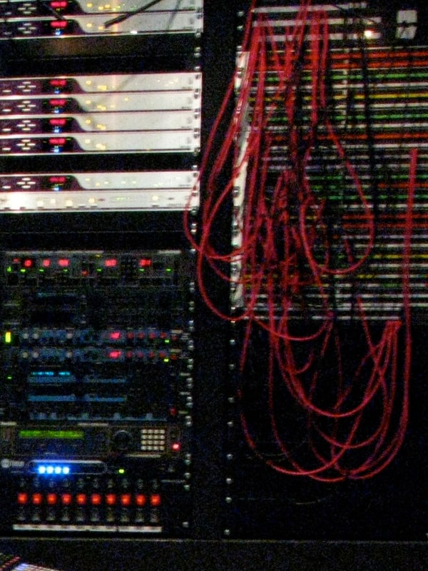 Studio patch bay with patch cords looped in the jackfield beside an outboard rack