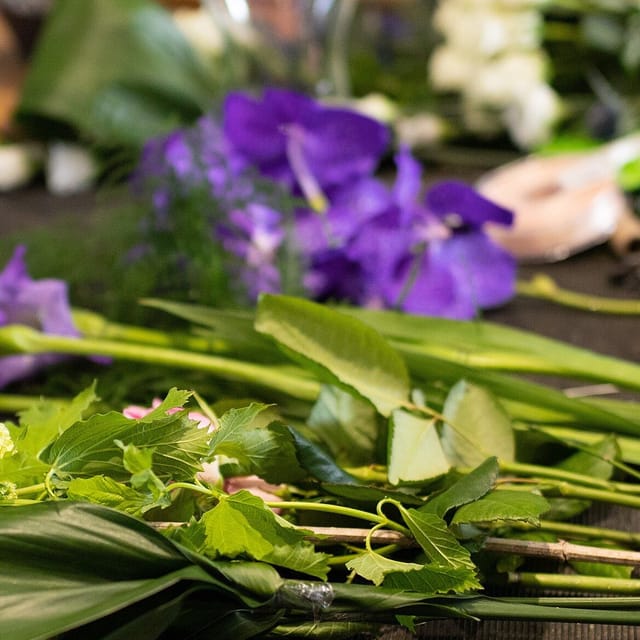 A closer crop of the same workbench: purple orchid heads resting against their cut stems.