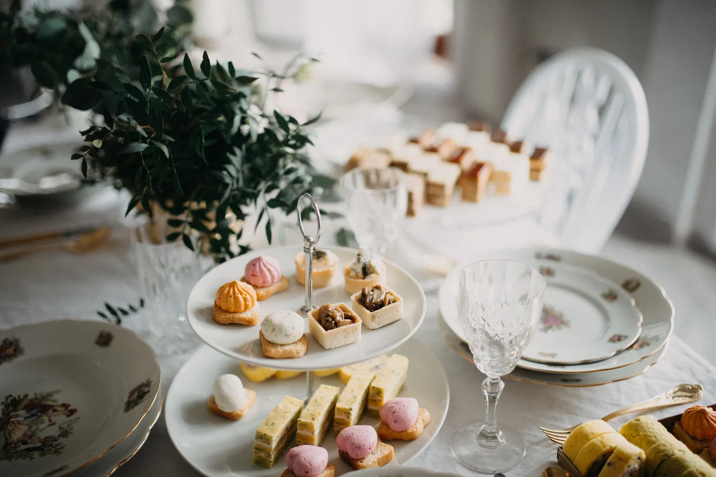 A tiered dessert stand of pastries and macarons on a dressed table.